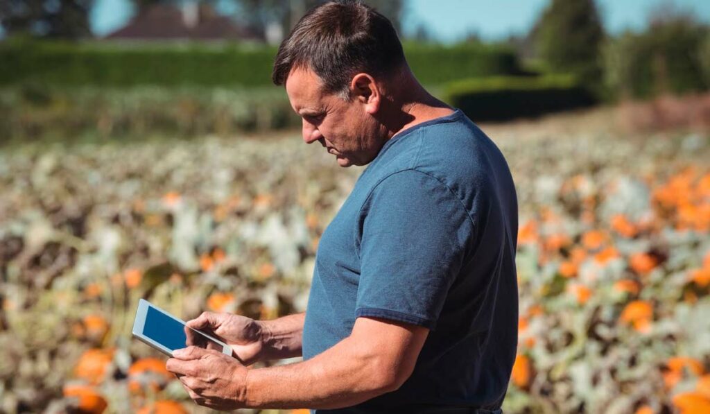 Agricultor com Ipad em mãos gerenciando sua lavoura