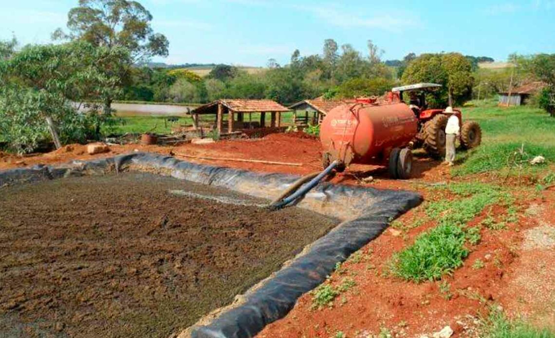 Esterqueira construída com geomembrana e agricultor abastecendo tanque de adubo orgânico para distribuição na lavoura ou pastagem