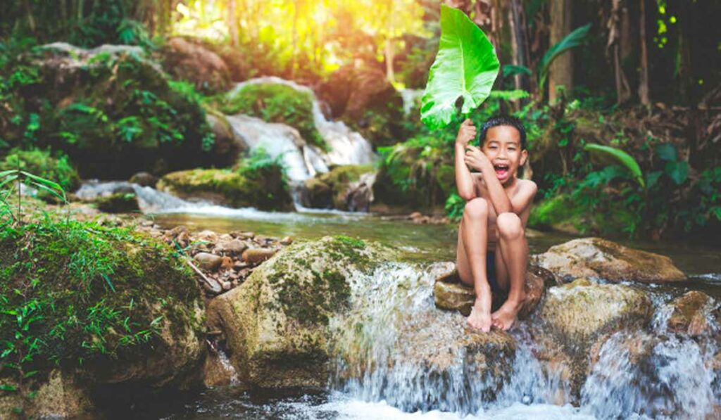 Menino mergulhando no riacho de águas límpidas