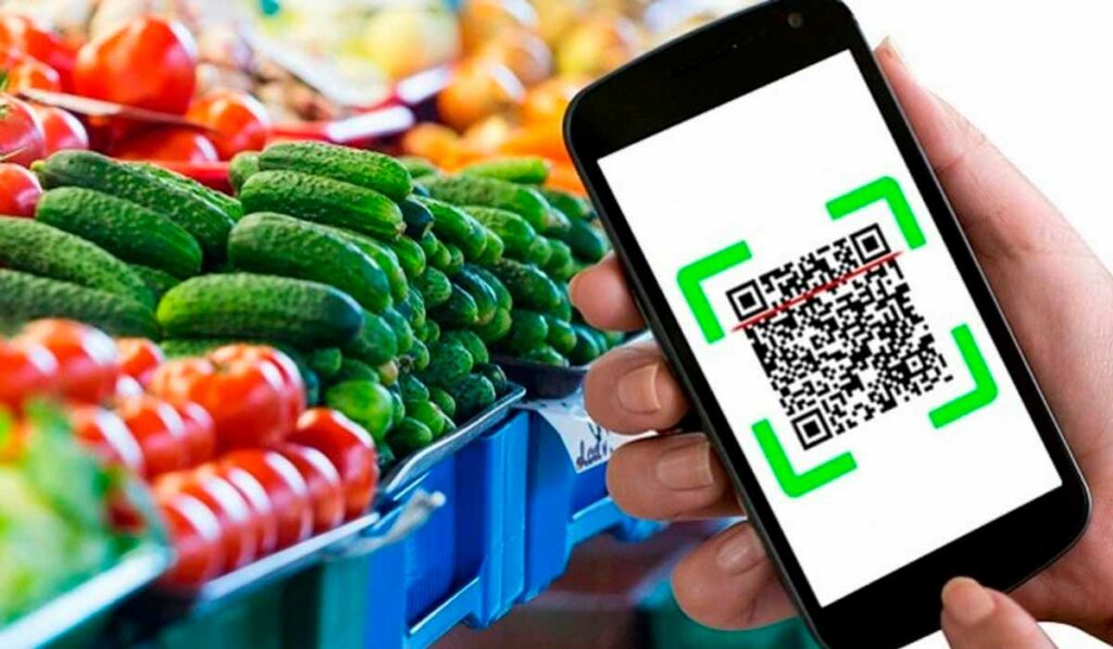 Consumidor com celular na mão verificando QR Code de hortifrutis no supermercado