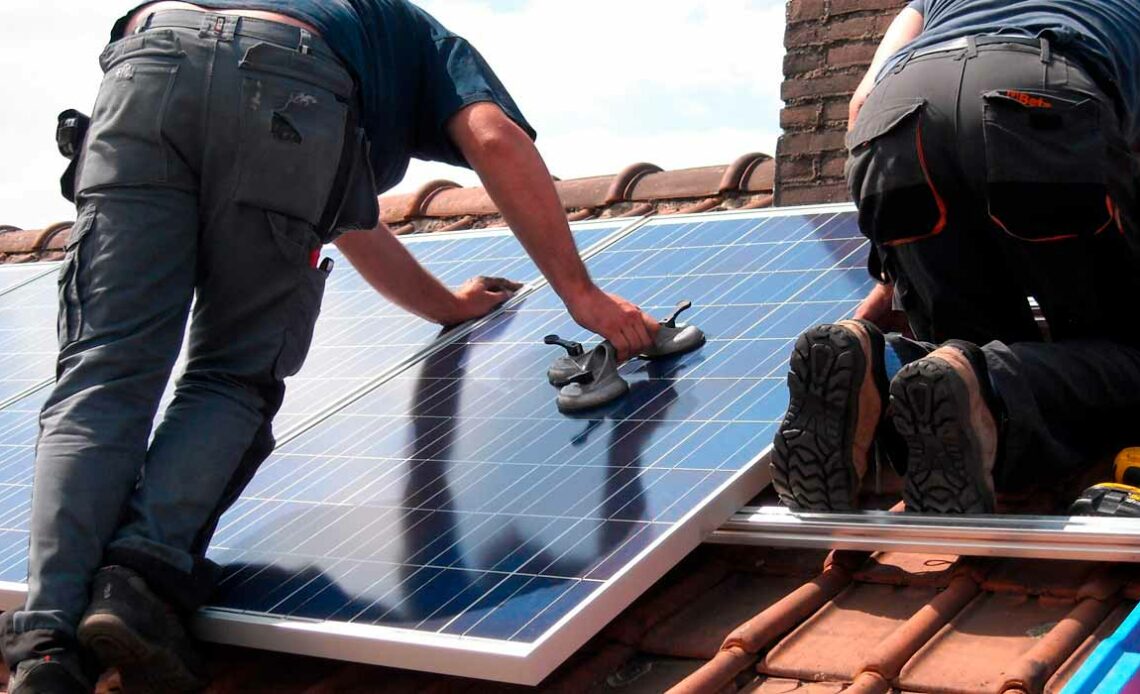 Homens instalando sistema de energia solar sobre o telhado de uma residência