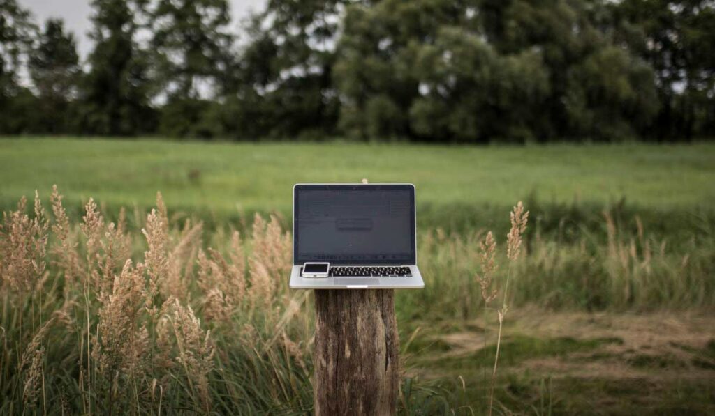 Internet rural - laptop e celular sobre um moirão na área rural