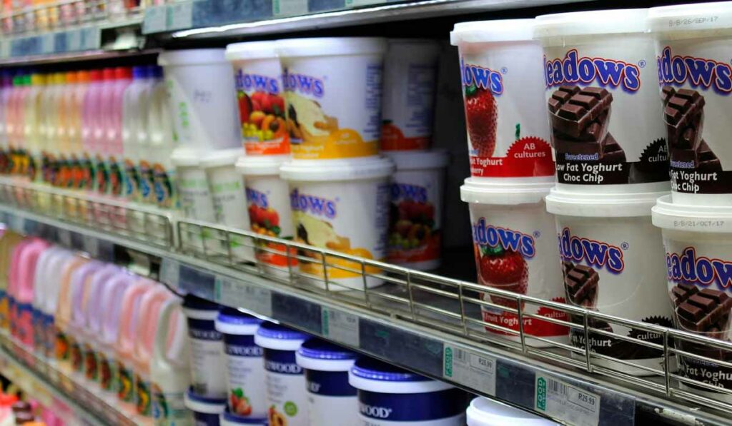 Prateleira de refrigerador em supermercado com produtos lácteos como iogurtes
