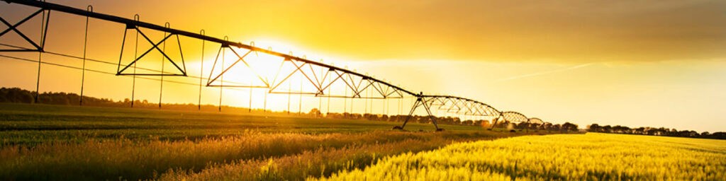 Sistema de irrigação através de pivot com por do sol ao fundo