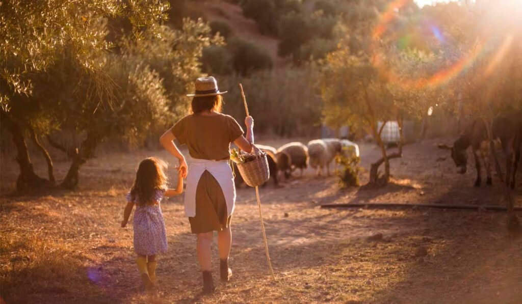Agricultora pastoreando ovelhas com a filha ainda criança