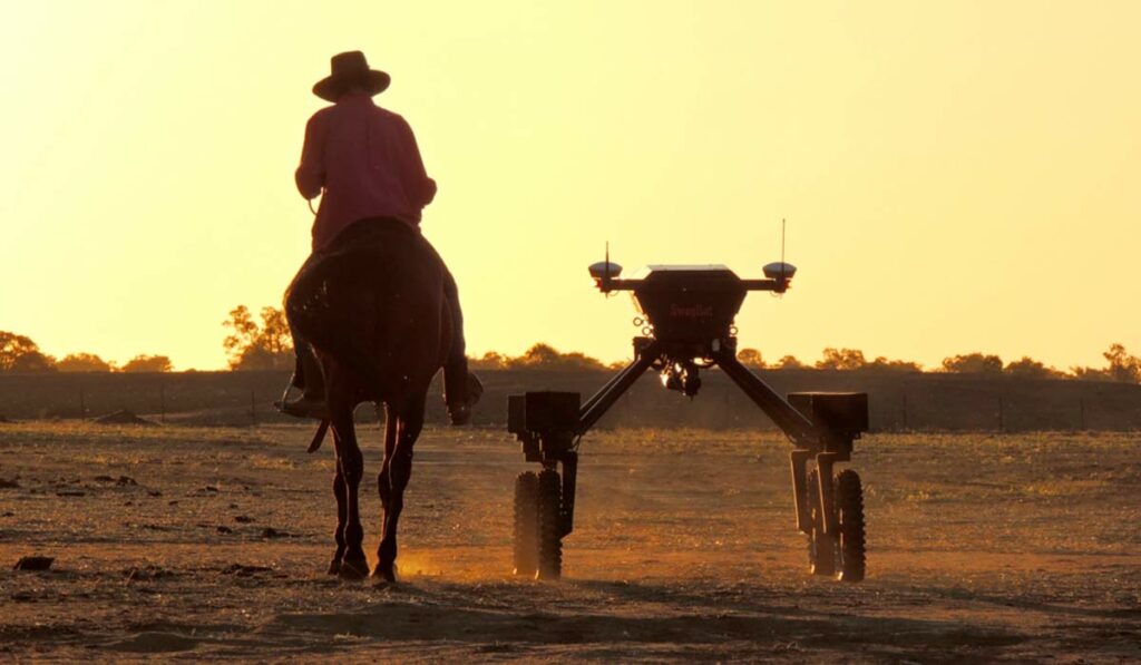 Fazendeiro a cavalo acompanhado por um robot agrícola