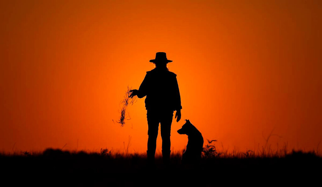 Fazendeira com seu cão no por do sol