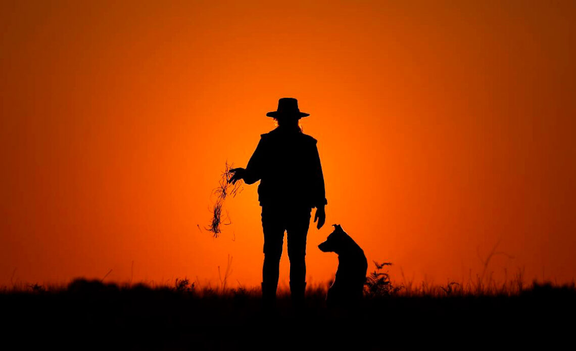 Fazendeira com seu cão no por do sol