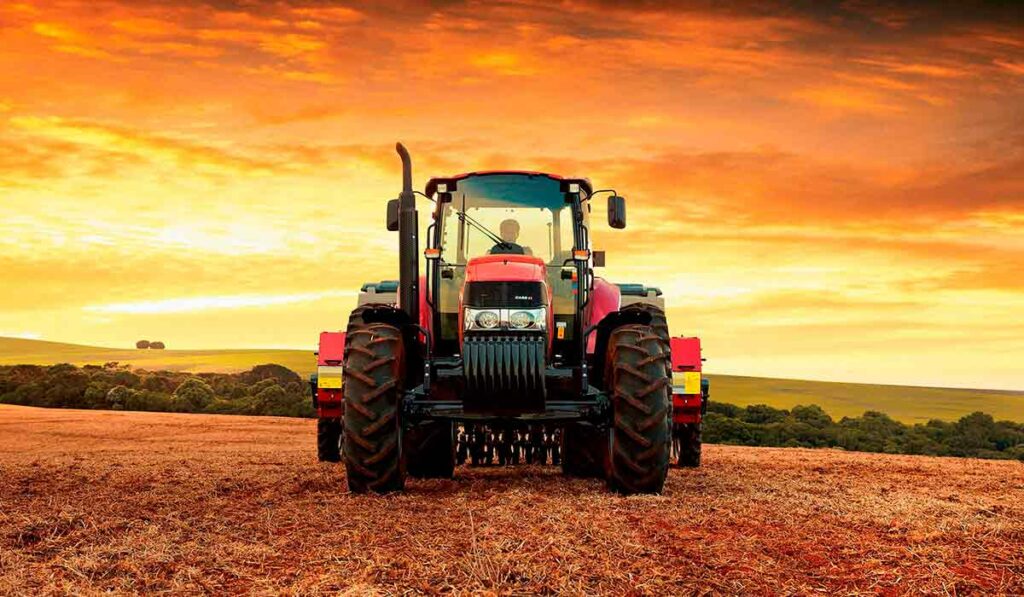 Trator em operação no campo com o por do sol ao fundo