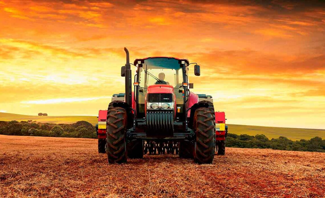 Trator em operação no campo com o por do sol ao fundo