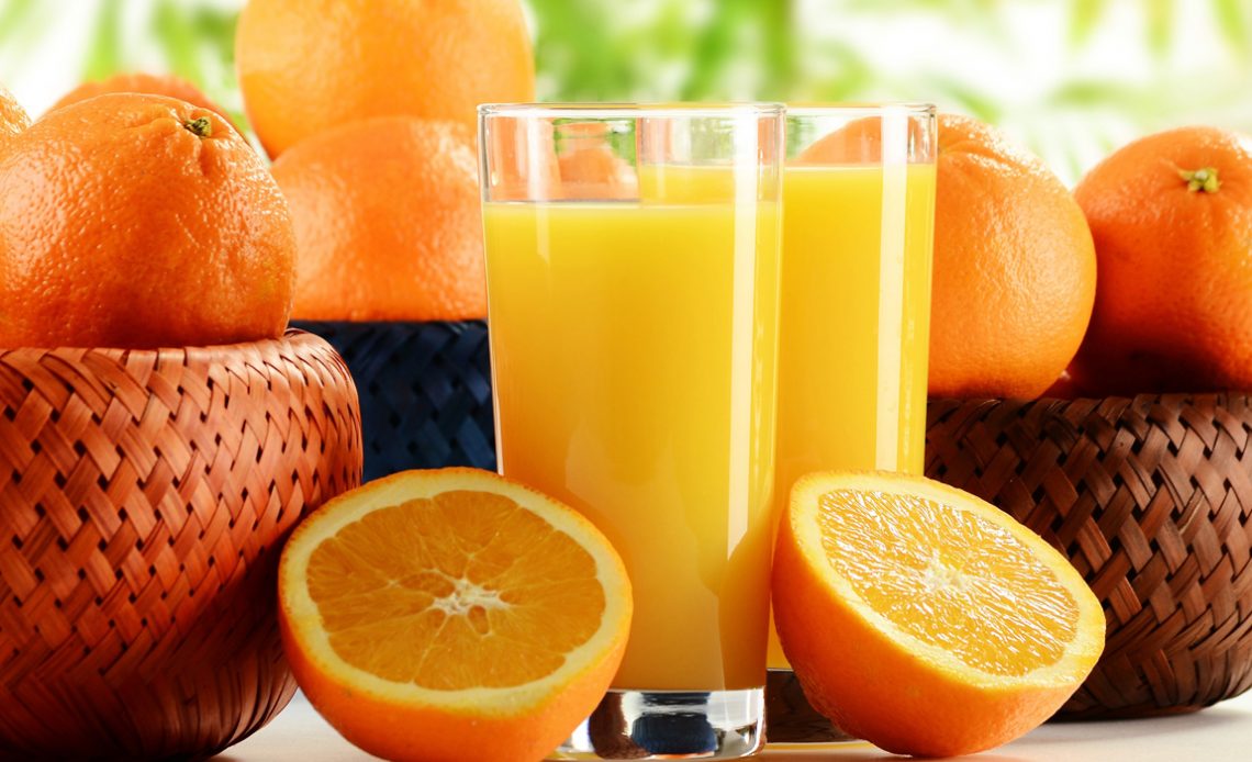 Copos de suco de laranja com frutos em cestas sobre a mesa
