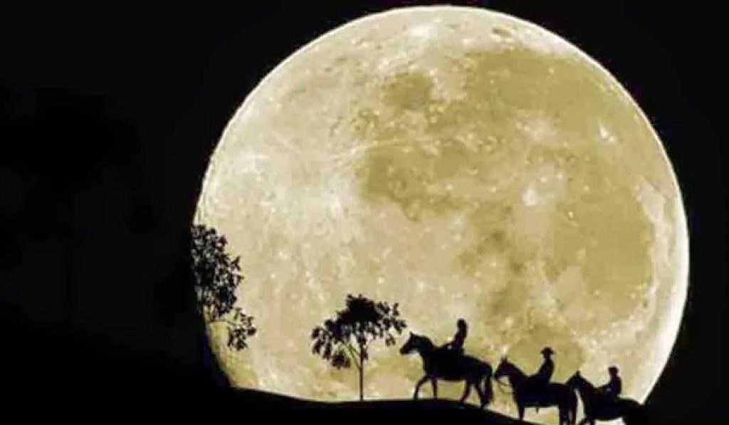 Cavalgada noturna com lua cheia ao fundo