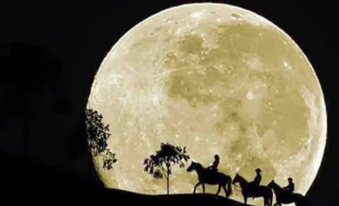 Cavalgada noturna com lua cheia ao fundo