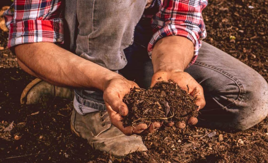 Produtor rural com um punhado de solos nas mãos