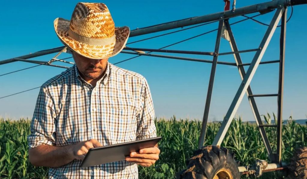 Agricultor com tablet no campo junto ao pivot de irrigação