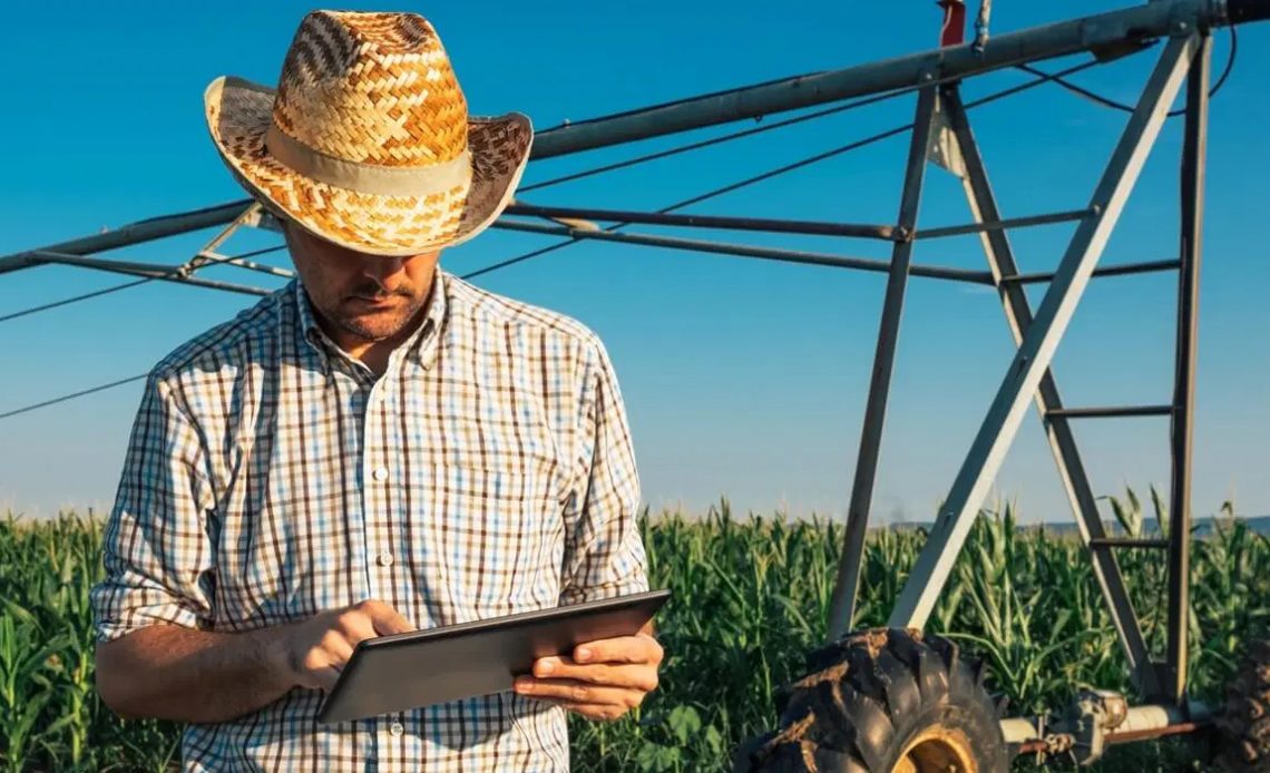 Agricultor com tablet no campo junto ao pivot de irrigação