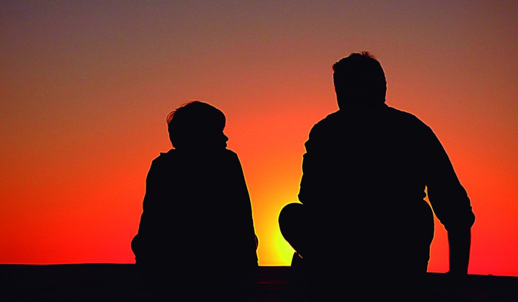 Pai e filho num final de tarde conversando ao por do sol sobre a empresa rural da família