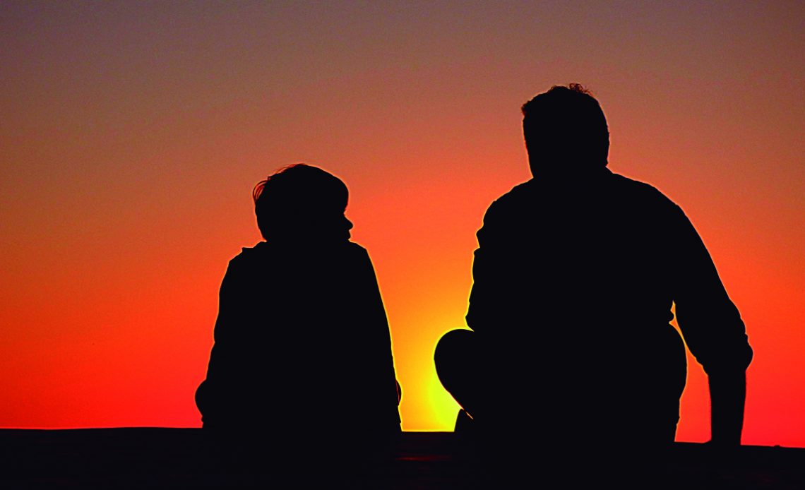 Pai e filho num final de tarde conversando ao por do sol sobre a empresa rural da família