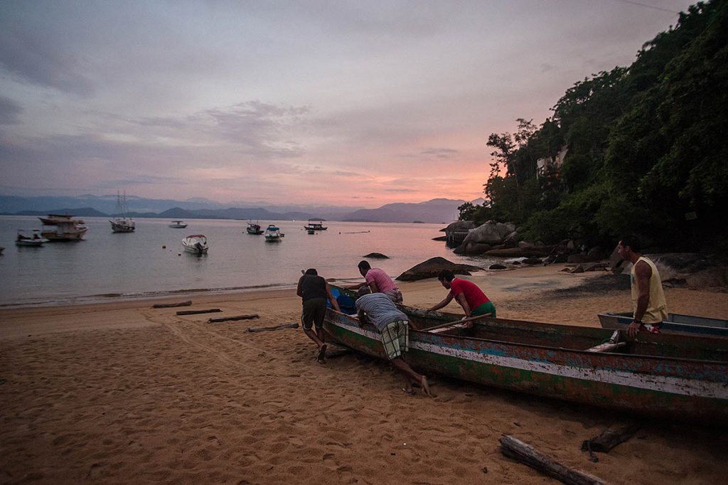 Pescadores artesanais empurrando a canoa para o mar - Foto: Boris Mercado