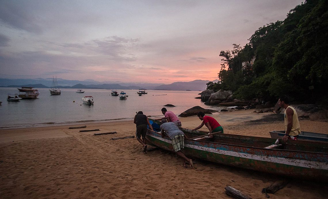 Pescadores artesanais empurrando a canoa para o mar - Foto: Boris Mercado