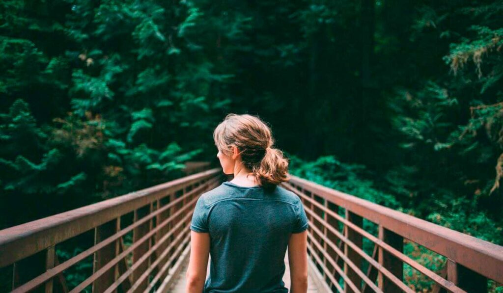 Ecoturista caminhando sobre uma ponte na floresta