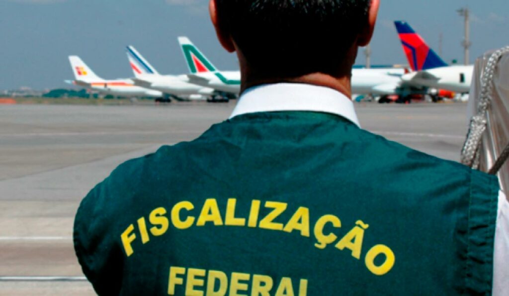 Agente da Fiscalização Agropecuária Federal em aeroporto com aviões ao fundo