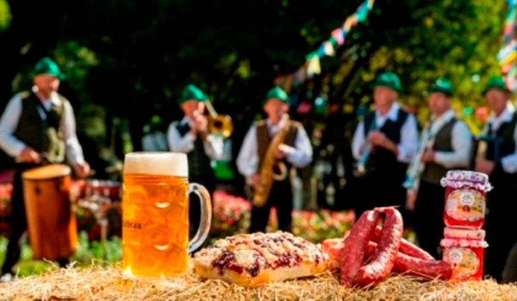 Caneca de chopp e embutidos com bandinha alemã ao fundo