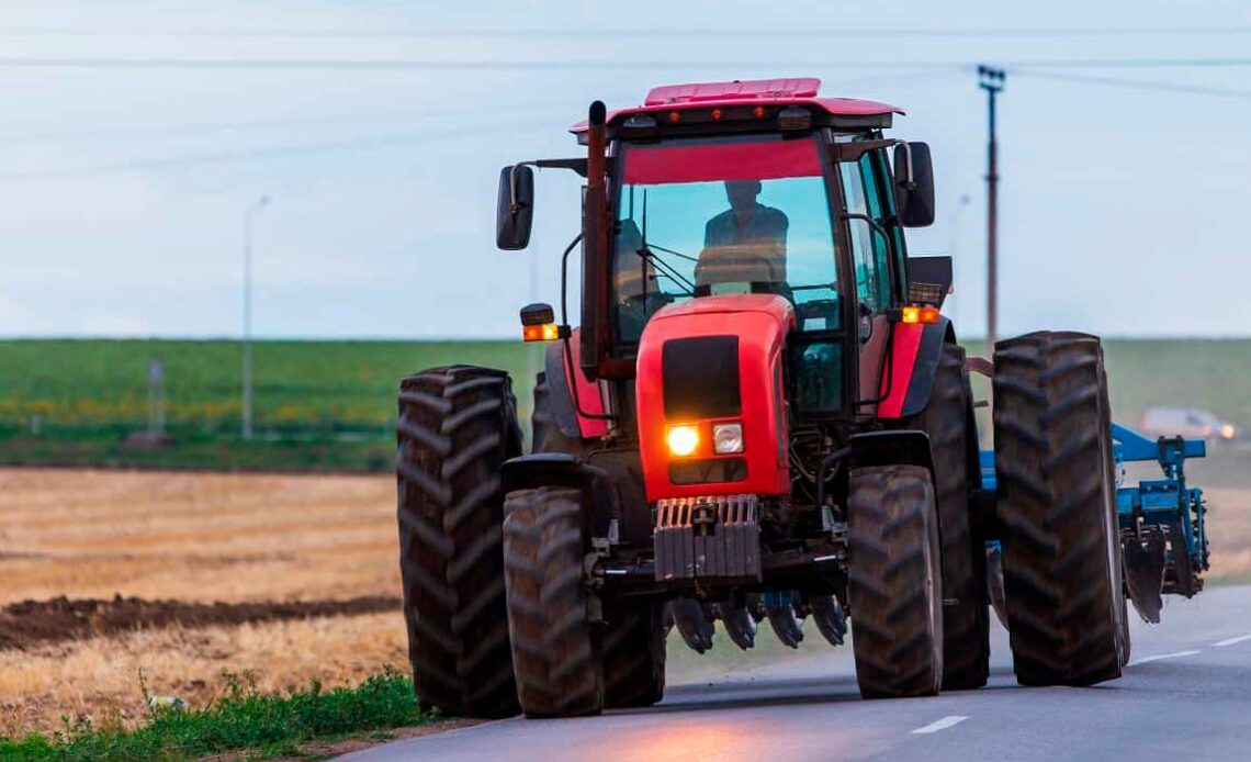 Trator equipado com grade circulando por estrada pública