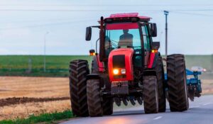 Trator equipado com grade circulando por estrada pública