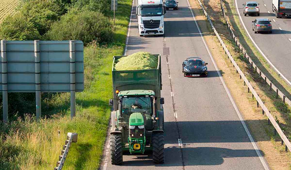 Trator equipado circulando em via pública de pista dupla com alta circulação