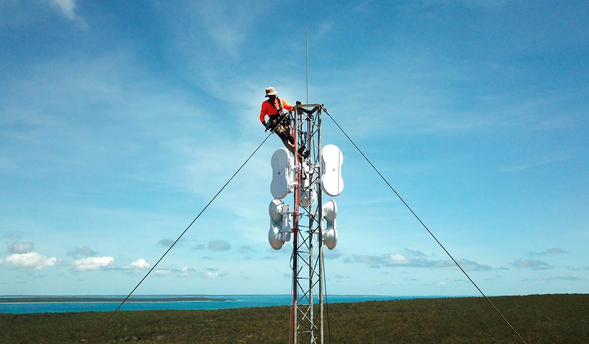 Técnico finalizando a instalação de antena na área rural