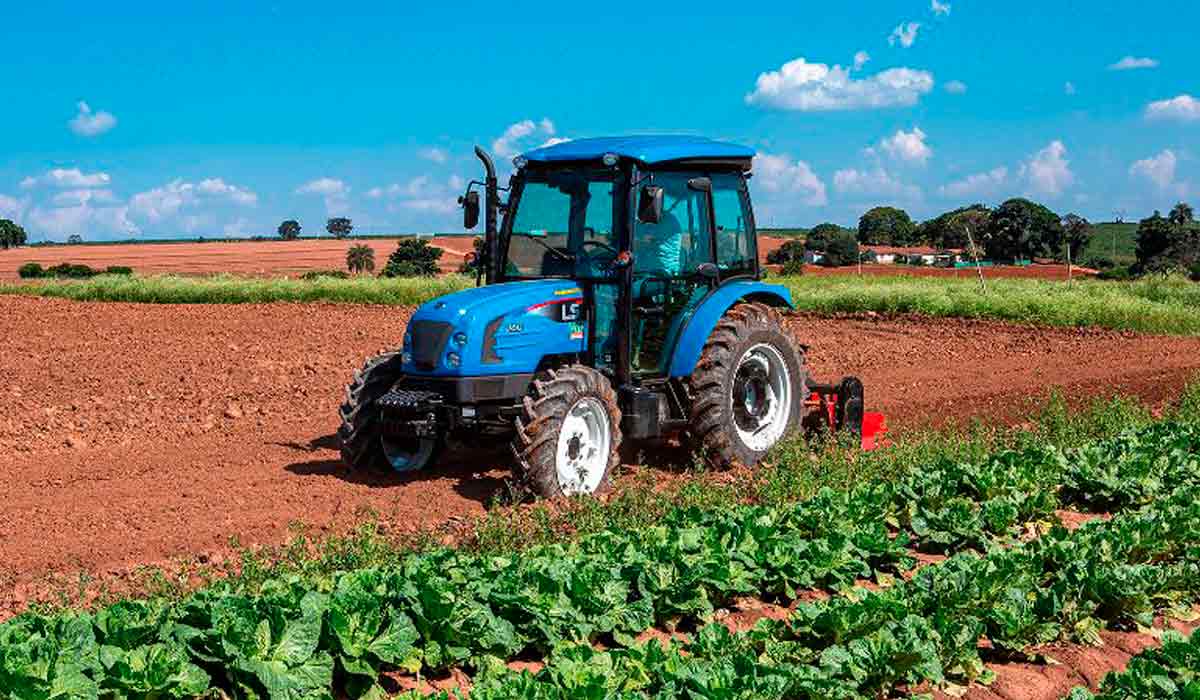 Trator de pequeno porte com cabine climatizada e tecnologia embarcada em operação na lavoura