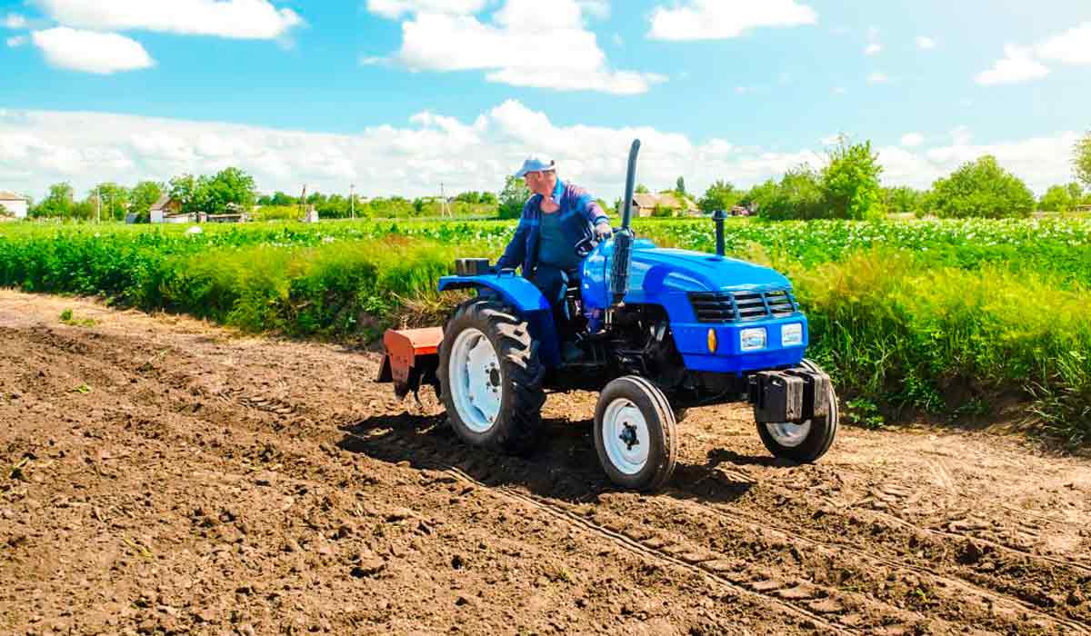 Agricultor familiar operando um pequeno trator na sua lavoura