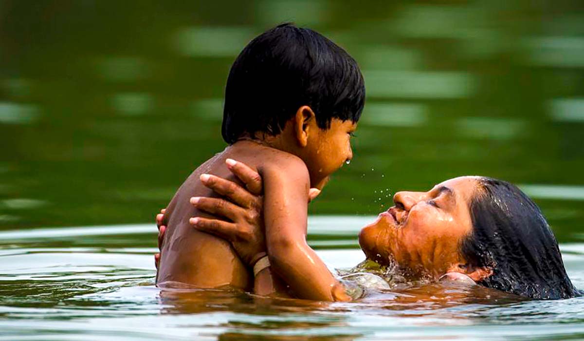 Mãe e criança indígena no banho de rio