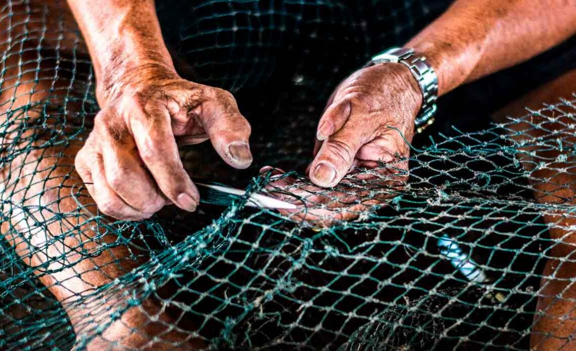 Pescador reparando sua rede de pesca