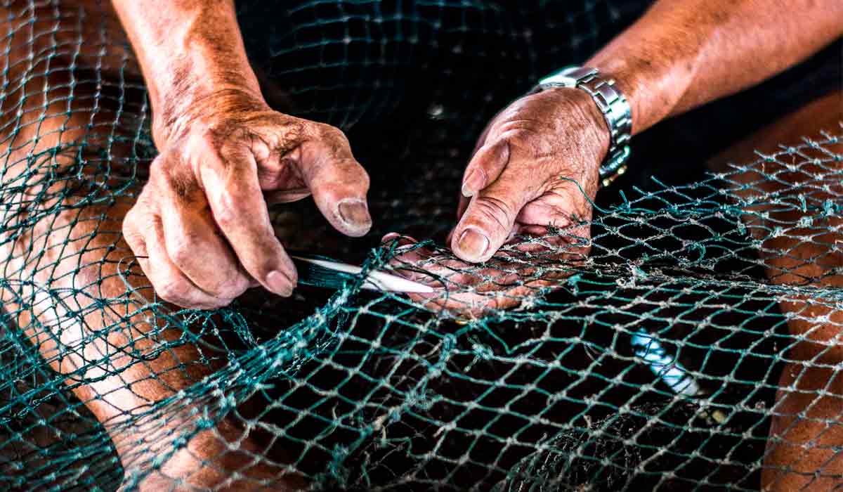 Pescador reparando sua rede de pesca