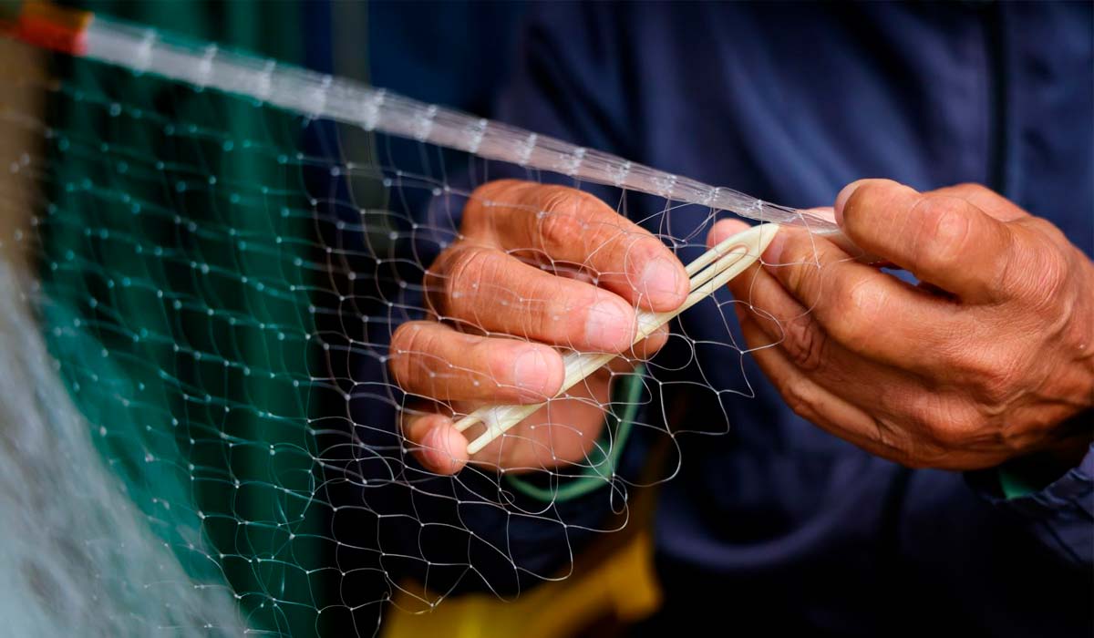 Pescador artesanal reparando sua rede de pesca Pescador artesanal reparando sua rede de pesca