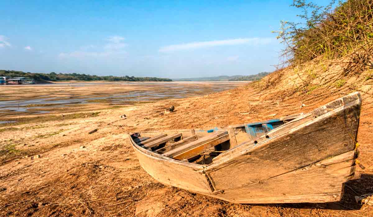 Leito de rio seco, com bancos de areia expostos e embarcação encalhada, retratando a seca Leito de rio seco, com bancos de areia expostos e embarcação encalhada, retratando a seca