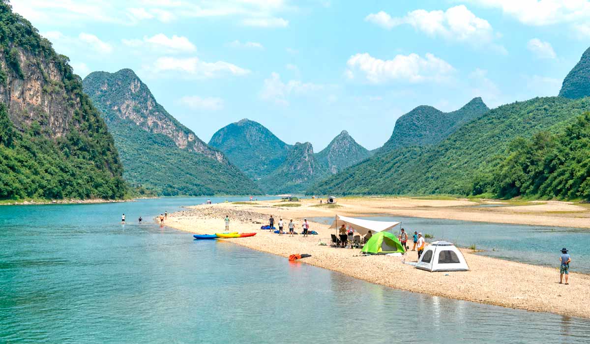 banco de areia com campings, caiaques e visitantes