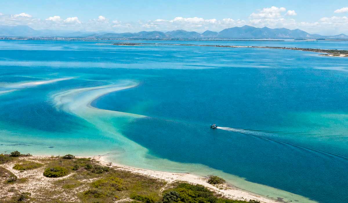 Vista aérea da maior laguna hipersalina do mundo, com águas calmas e vegetação de restinga ao redor Vista aérea da maior laguna hipersalina do mundo, com águas calmas e vegetação de restinga ao redor